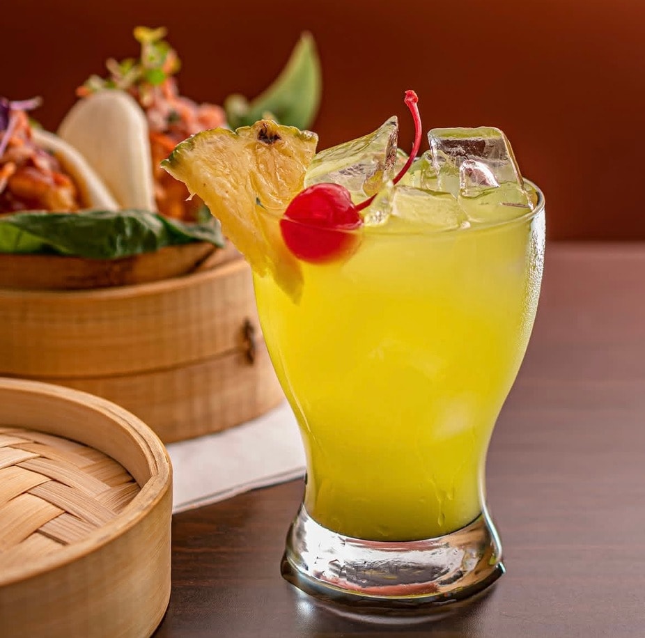 Yellow pineapple cocktail with cherry garnish